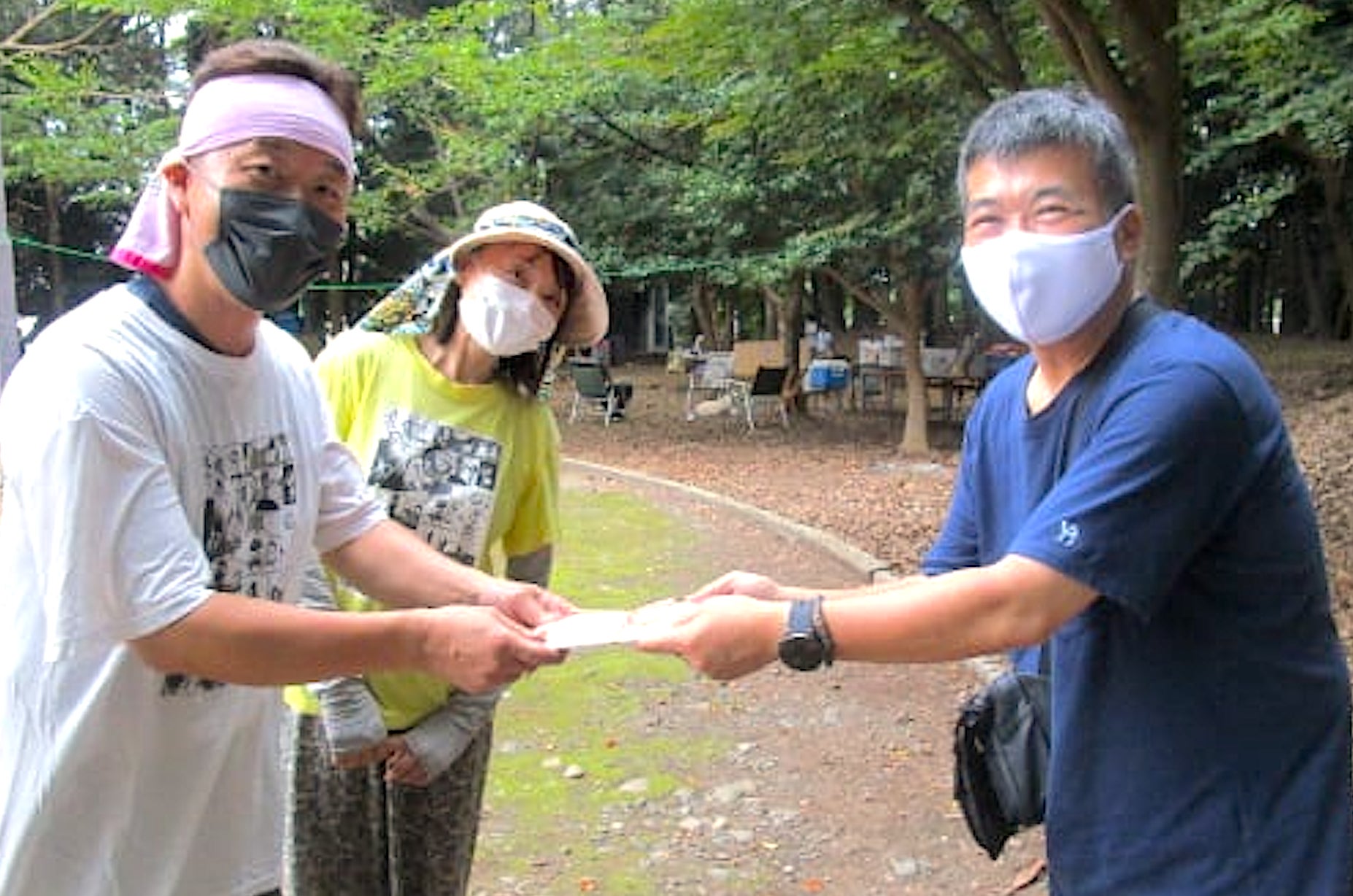 子ども食堂（NPO法人ゆめ・まち・ねっと）代表渡部達也氏〈左〉、渡部美樹氏〈中央〉に、寄付金を手渡す文理学院社長小倉勤氏〈右〉（2021年の様子）